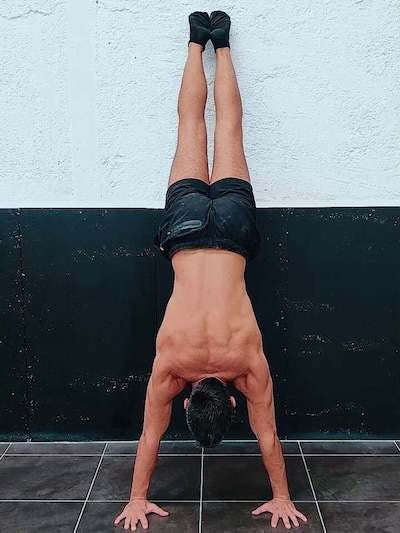 Handstand with posterior pelvic tilt facing the wall