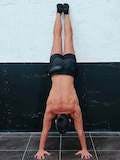 Handstand with posterior pelvic tilt facing the wall